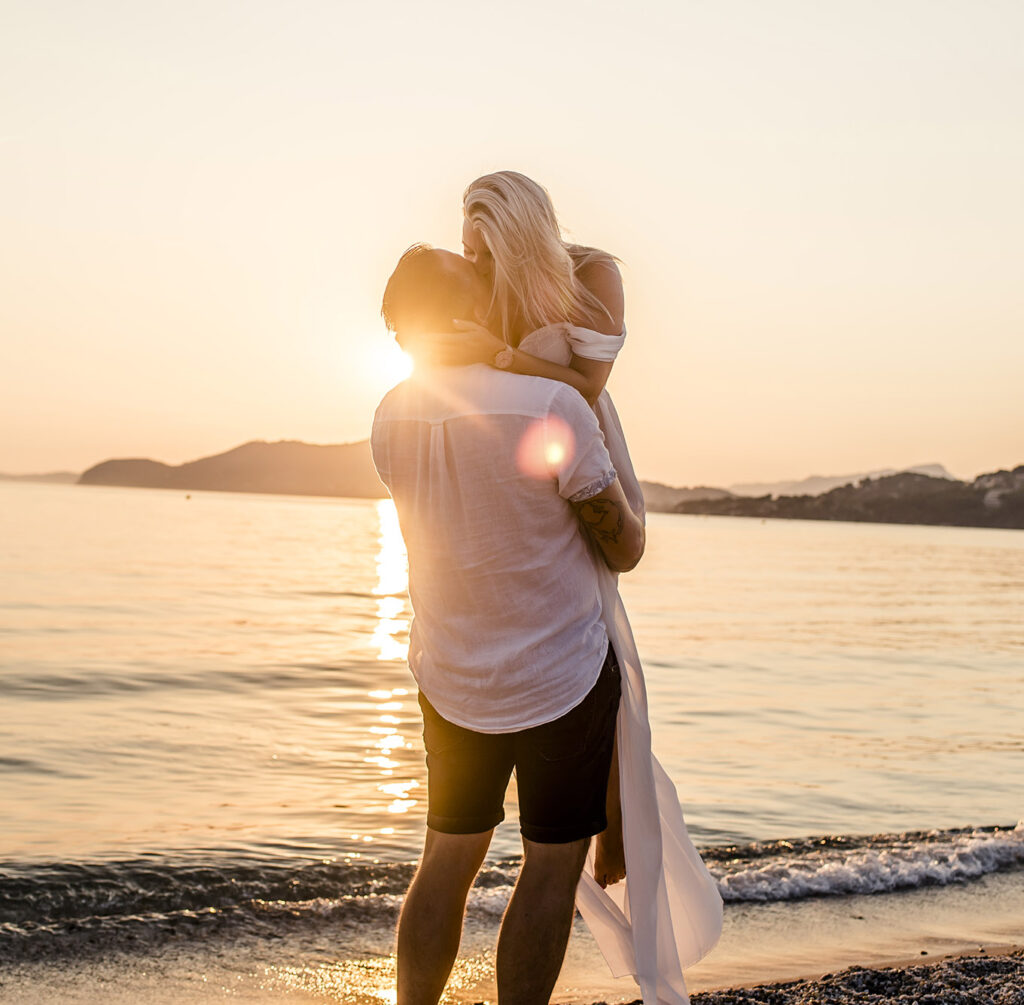 Photo grossesse à Hyères, couple enlacé sur la plage au coucher du soleil