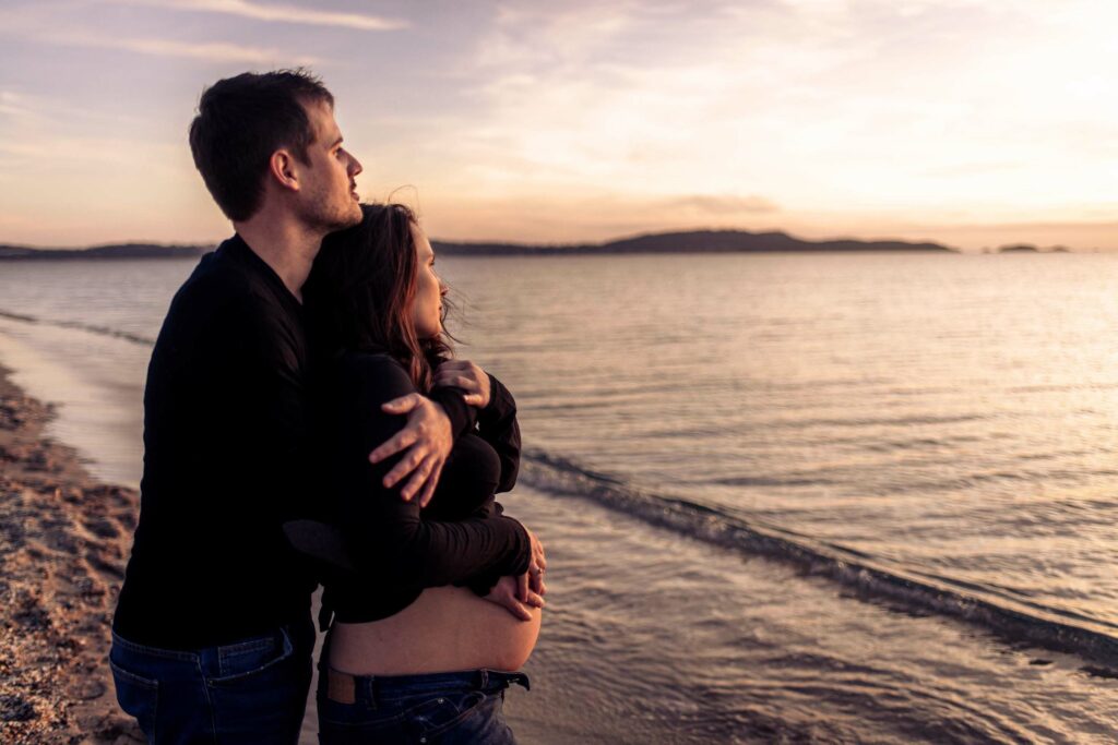 Photo grossesse à Hyères, couple enlacé sur la plage au coucher du soleil