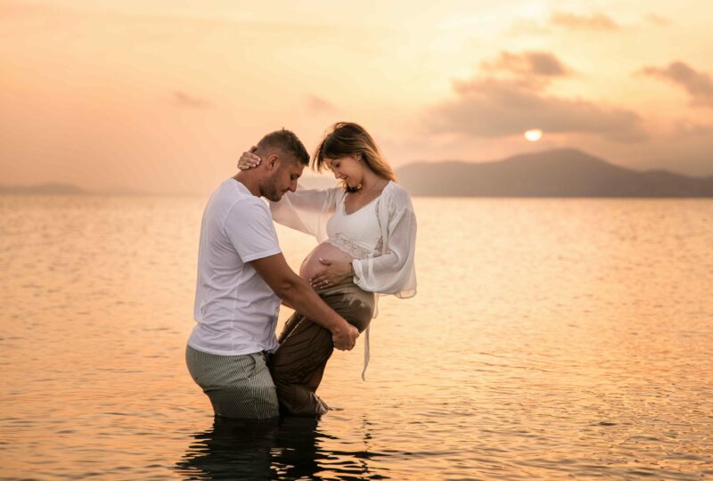 Photo grossesse à Hyères au coucher du soleil, couple dans l’eau en lumière dorée