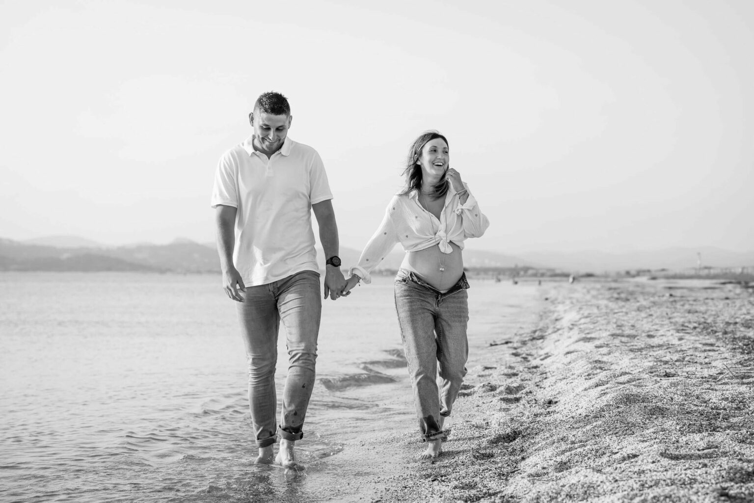 Photo grossesse en couple sur la plage à Hyères, marche dans l’eau en noir et blanc