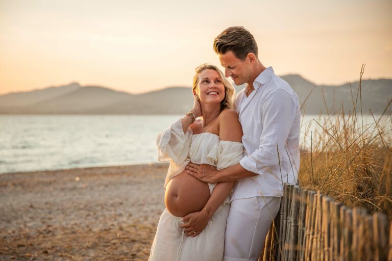 Photo grossesse en couple à Hyères, femme enceinte en robe blanche au coucher du soleil