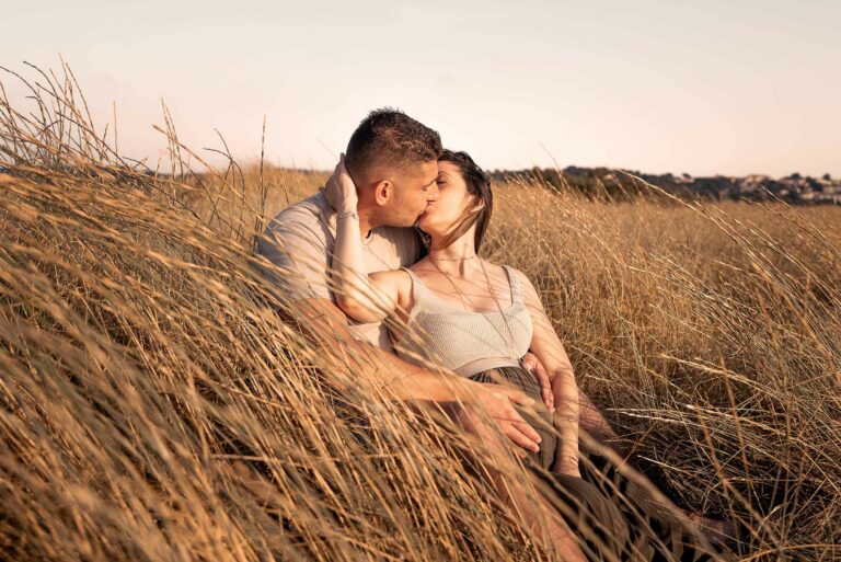 Photo grossesse dans les herbes dorées à Hyères, couple s’embrassant au coucher du soleil