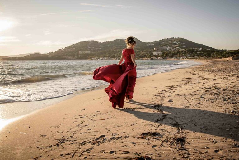 Séance photo lifestyle d’une femme en robe rouge sur la plage, lumière naturelle